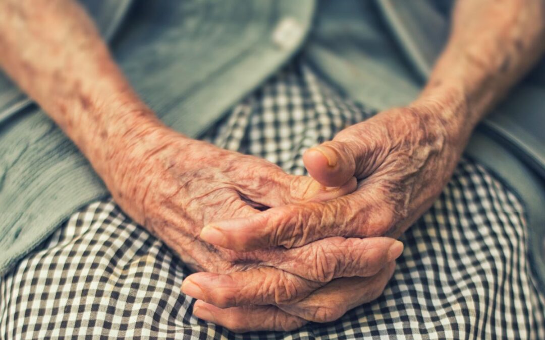 Wrinkled women's hands folded in lap