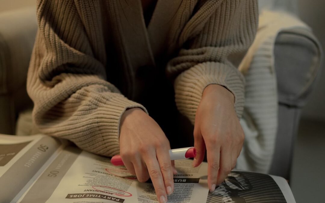 Young woman reading newspaper with pen in hand to circle job offers