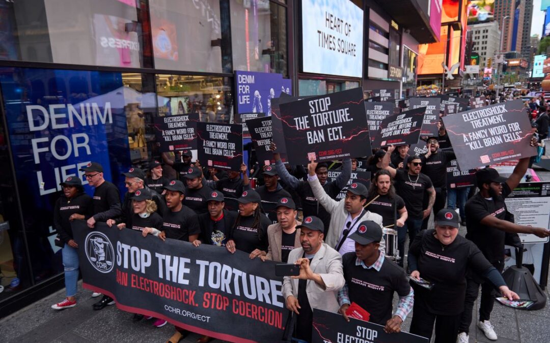 Marching people with protest signs "stop the torture"