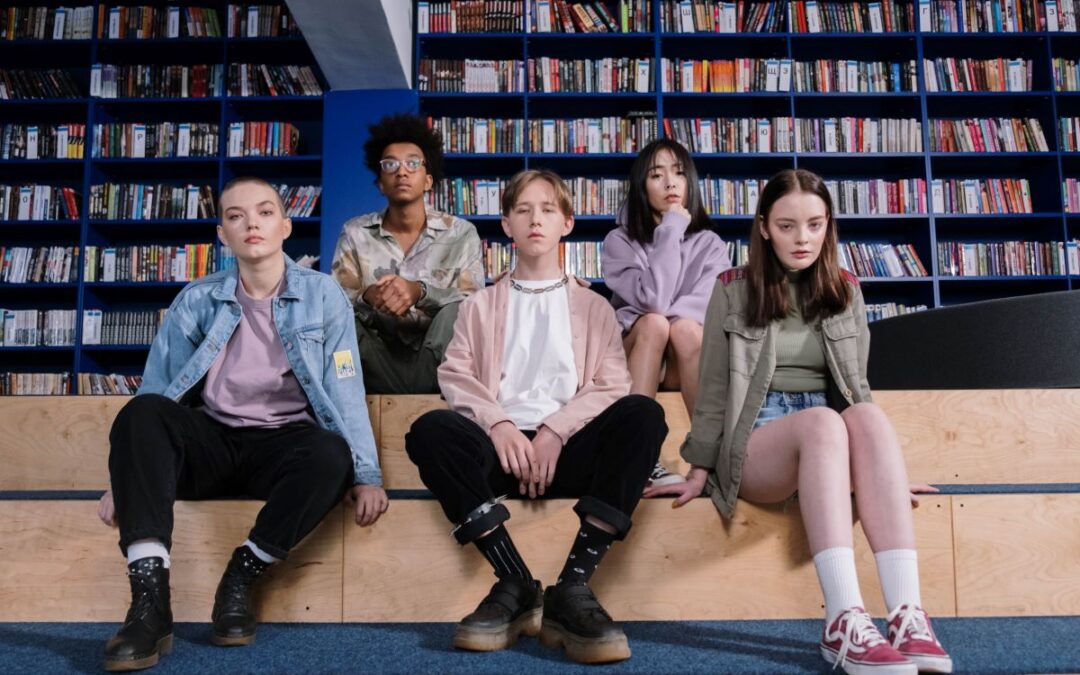 School children sitting on steps in front of shelves in background