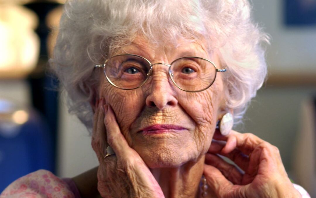 Older woman with glasses and white hair looking at the camera.