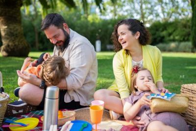 Parents with 2 small children sitting on grass with picknick blanket