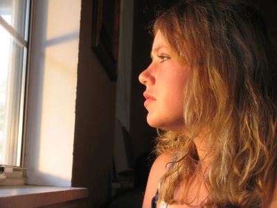 Young woman with long brown hair is looking out the window