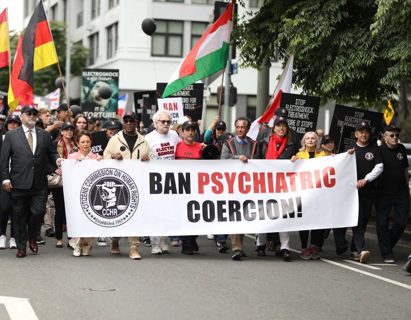 People marching behind a banner saying Ban Psychiatric Coercion