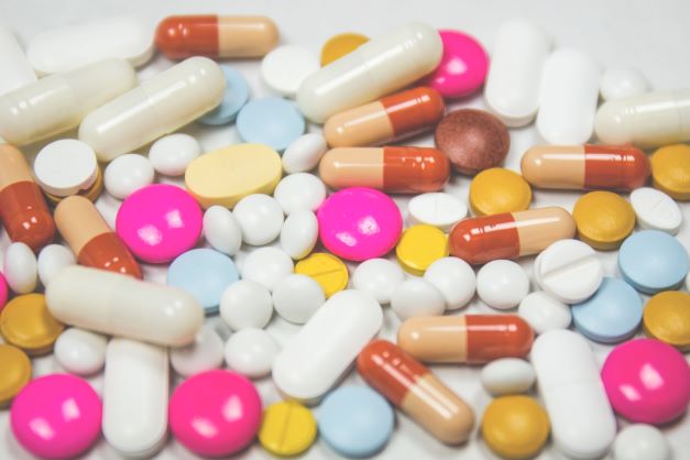 Lots of different, colorful pills in a heap on a white surface