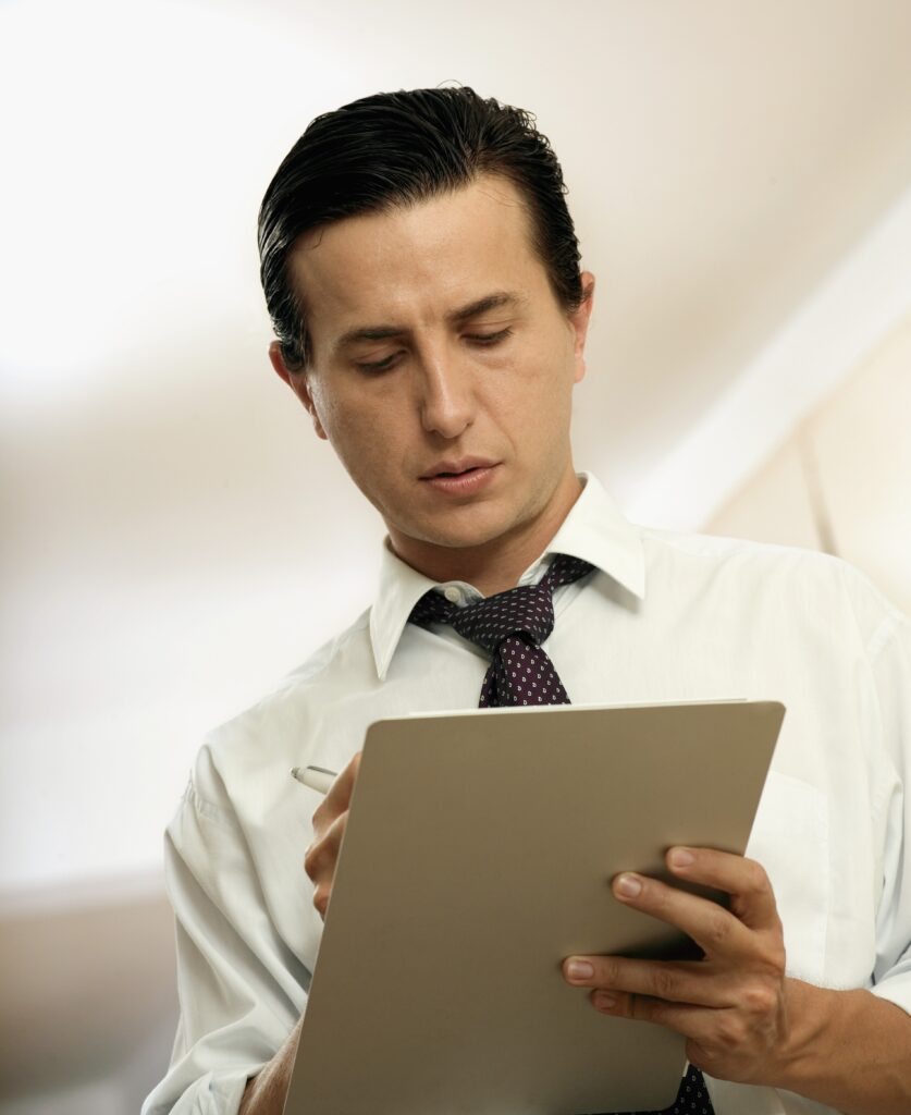 Man with white shirt looking down on clipboard, seeing from below clipboard