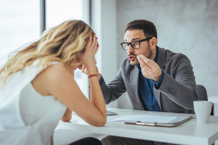 Man with dark hair berating a distraught woman with blond hair