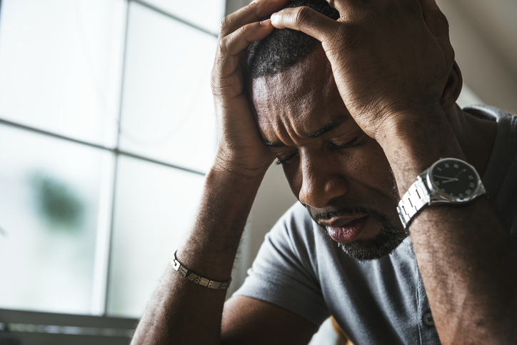 Black man sitting in front of window looking in despair