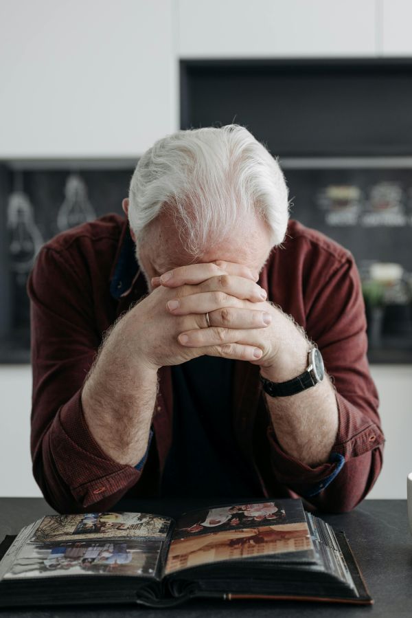 Man with folded hands against forehead looking down at photo album