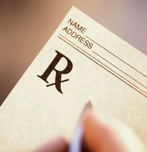Rx pad with yellow background and hand with pen