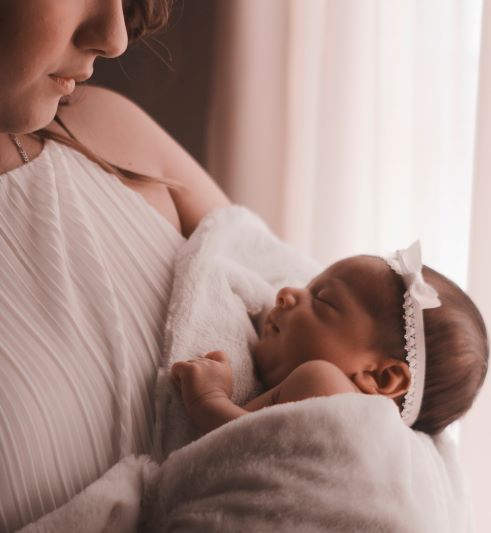 Woman looking down at tiny girl baby in her arms.
