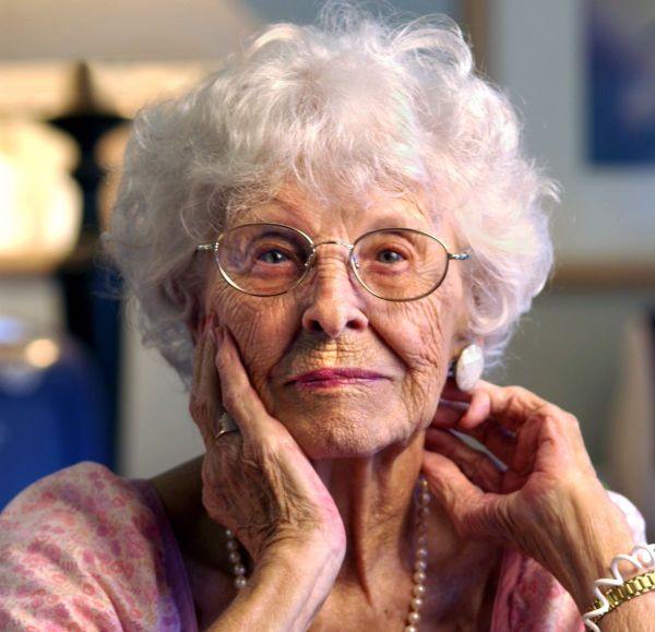 Older woman with white, curly hair looking into the camera