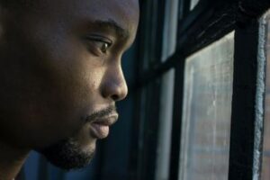 Black man, serious, looking out window