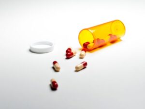 Open orange pill container with pills spilling out